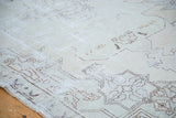 Distressed Oushak rug texture with faded ivory and sea foam green minimalist patterns.