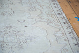 Distressed Oushak rug texture with faded beige and charcoal geometric outlines.