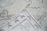 Distressed Oushak rug corner reveals hand-knotted backing and faded geometric pattern.