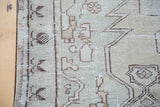 Distressed texture of a vintage Oushak rug with faded sea foam green and charcoal patterns.