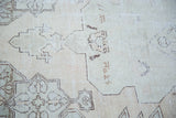 Faded texture of distressed Oushak rug, minimalist pattern in ivory, beige, charcoal.