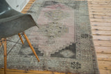 Distressed blush rose Oushak rug, showing geometric border and fringe.