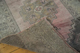 Distressed hand knotted Oushak rug corner, revealing sturdy backing and rose field.