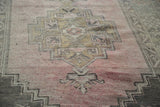 Textured view of vintage distressed Oushak rug, blush rose field with geometric grey patterns.
