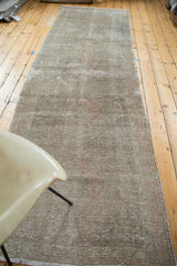 Distressed vintage Oushak runner rug showcasing muted geometric medallions in earthy beiges and blush.