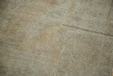 Textured neutral pile of the distressed Oushak rug, showing wear and a distinct dark stripe.