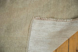 Distressed Oushak rug corner revealing textured pile, short fringe, and hand-knotted foundation.