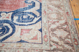 Distressed Oushak rug detail with faded navy arabesque and textured cherry red, ivory field.