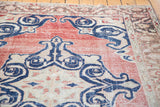 Distressed Oushak rug, navy scrolling islimis on faded red field, subtle horizontal striation.