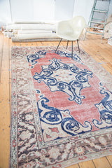 Distressed Oushak rug, central geometric medallion with scrolling arabesques, faded red and blue.