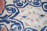 Navy blue scrolling arabesques with faded red accents and soft distressed pile texture.