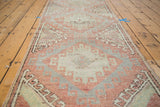 Distressed Oushak runner showing tribal hook gul design in faded red, sea foam, and grey.