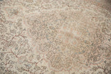 Distressed Oushak carpet pile showing faded intricate floral patterns in ivory, blush, and blue.