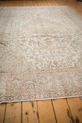 Distressed Oushak rug, faded intricate floral patterns in antique ivory, blush, and light blue.