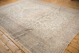 Distressed Oushak carpet corner, revealing faded curvilinear patterns in ivory, rose, and blue.