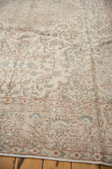 Decorative distressed texture of Oushak rug border with faded blush and blue motifs.
