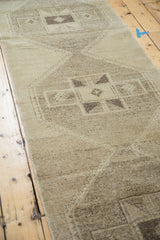 Distressed Oushak runner with faded beige gold pile and geometric charcoal pattern.