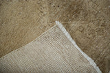 Distressed Oushak rug pile texture with visible hand-knotted foundation and ivory fringe.