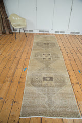 Distressed Oushak runner's geometric medallion in beige gold, soft charcoal, and ivory fringe.