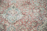 Distressed Oushak rug showing faded blush rose, celadon green, and ivory curvilinear pattern.