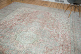 Distressed Oushak carpet edge detail with faded celadon, blush rose, and ivory motifs.
