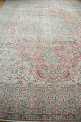Distressed Oushak carpet border, with faded celadon green, blush rose, and ivory patterns.