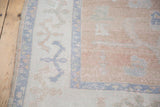Decorative distressed Oushak rug corner with primitive motifs in faded apricot, dusty blush, sky blue.