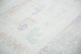 Distressed Oushak carpet with faded ivory pile and primitive mint green, blush rose motifs.