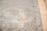 Vintage distressed Oushak carpet with muted green border, running hook design, and expressive cloudband.
