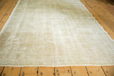 Close-up of distressed vintage Oushak rug showcasing worn texture and muted ivory beige pattern.