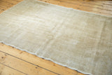 Muted ivory, beige, and grey distressed pile texture with a subtly worn edge on a Turkish Oushak rug.