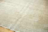 Distressed Oushak rug's muted ivory and beige tones, revealing worn texture and subtle design.