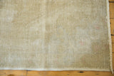 Worn texture of a distressed Oushak rug with muted ivory, beige, and rose colors, fringed edge.