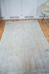 Textural distressed Oushak rug with faded vintage character in soft ivory, beige, and rose.