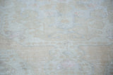 Distressed Oushak rug texture revealing faded ivory, beige, and soft pink rose.