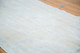 Faded ivory and beige pile of a distressed Oushak rug, featuring a wavy edge.