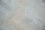 Textural detail of the distressed Oushak rug with muted ivory, beige, and soft rose.
