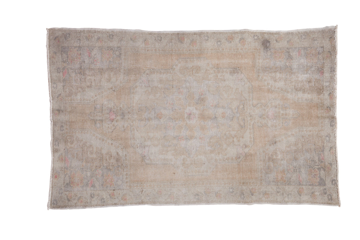 Distressed Oushak rug with faded medallion, powder pearl border, and muted beige and pink.