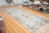 Distressed vintage Oushak runner with faded apricot peach and moss green tribal motifs.