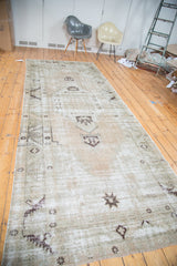 Distressed Oushak runner with faded apricot peach, moss green, and ivory geometric tribal motifs.
