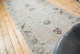 Distressed Oushak runner texture with faded apricot peach and moss green tribal patterns.