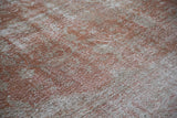 Artfully distressed Oushak carpet texture, showing faded brick red and subtle cream tones.