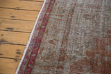 Faded red border and distressed brown-green pile texture on a vintage Oushak rug.