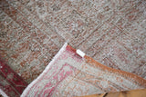 Distressed Oushak rug's folded corner reveals muted pile texture and colorful woven foundation.