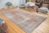 Textured pile of a distressed Oushak carpet, with faded brown and light beige tones.