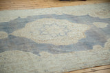Distressed Oushak rug's denim blue field with softened ivory medallion and trefoil motifs.