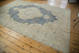 Distressed Oushak corner: softened ivory borders, light bark brown patterns, and fringe.