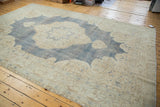 Distressed Oushak carpet texture with worn denim blue medallion and softened ivory field.