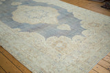 Distressed Oushak rug corner detail, softened ivory and blue trefoil motif.
