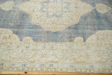 Distressed hand-knotted Oushak rug with ivory medallion, denim blue field, and decorative border.